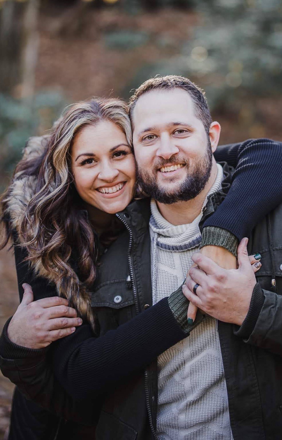 Daniela and Brian of Ferris View Media, smiling together outdoors among autumn trees